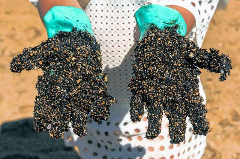 A volunteer shows his crude-encrusted gloves at Praia de Busca Vida beach in Bahia state during a cleanup operation on November 