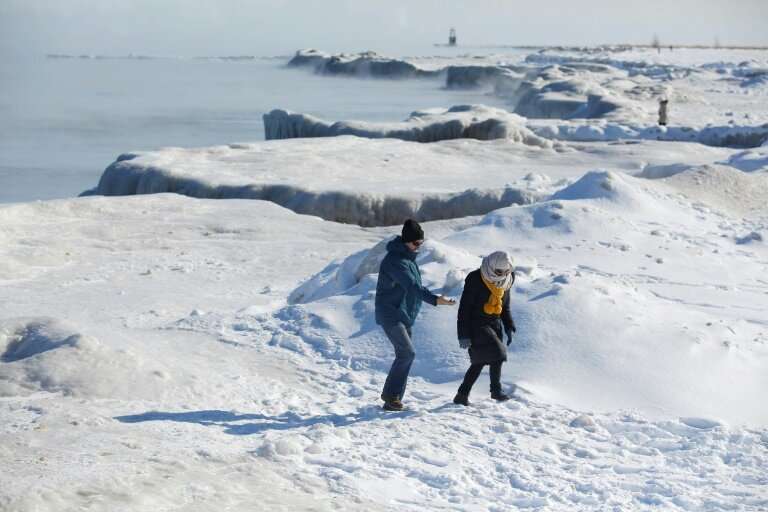 People walk along Lake Michigan's frozen shoreline as temperatures dropped to -20 degrees F (-29C) Chicago