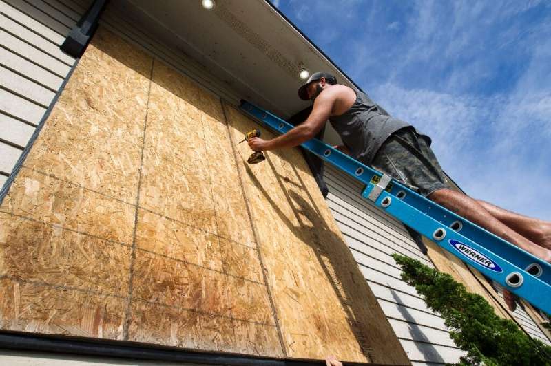 Tayler Hofe boards up the windows of a surf shop in Avon, North Carolina, as Hurricane Dorian approaches