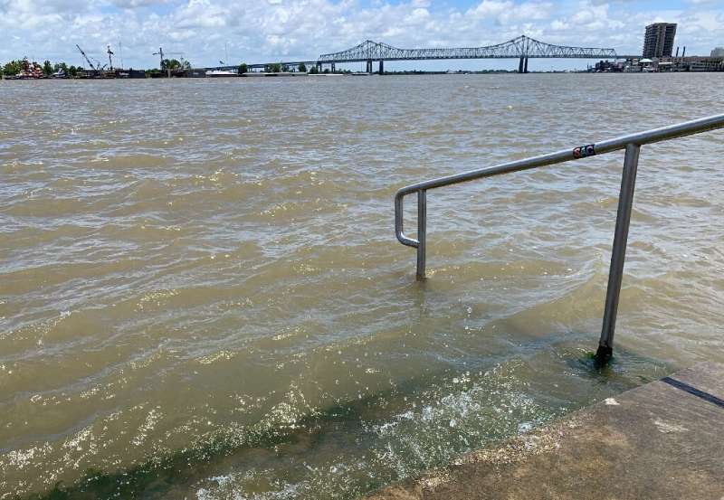 The swollen Mississippi River laps at the stairs on a protective levee in New Orleans
