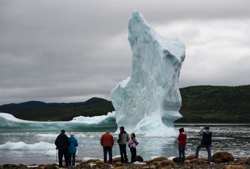 Tourists look at icebergs from the seashore of King's Point—May to July is peak viewing season, bringing thousands of visitors f
