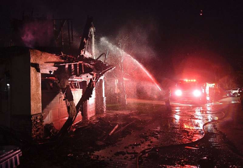 Firefighters hose down a burning house near Santa Clarita, California
