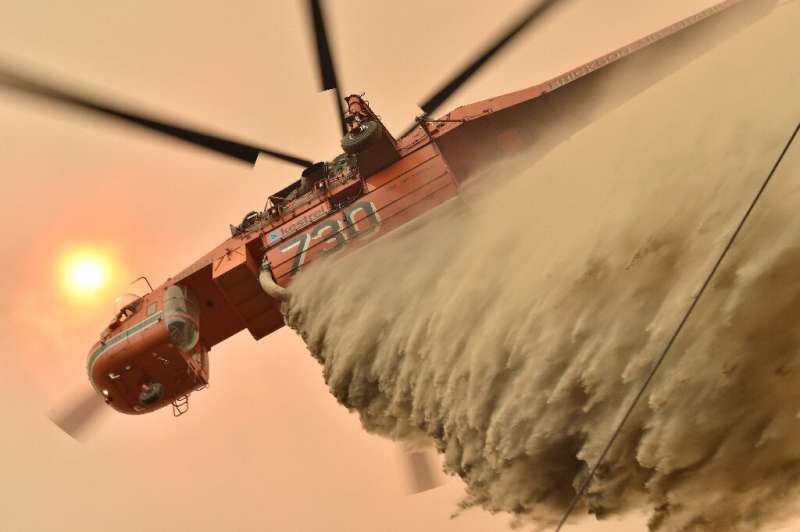 A helicopter drops fire retardent to protect a property on Australia's east coast