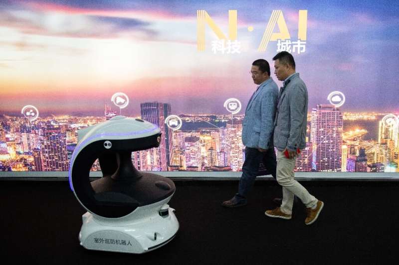 Visitors walk past a security robot named APV3 with a facial recognition system at the 14th China International Exhibition on Pu