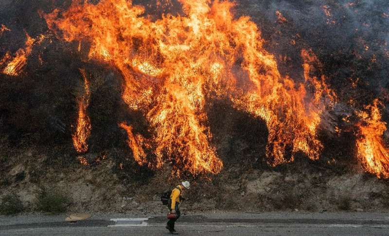 A firefighter walks near flames during the Saddleridge fire in southern California