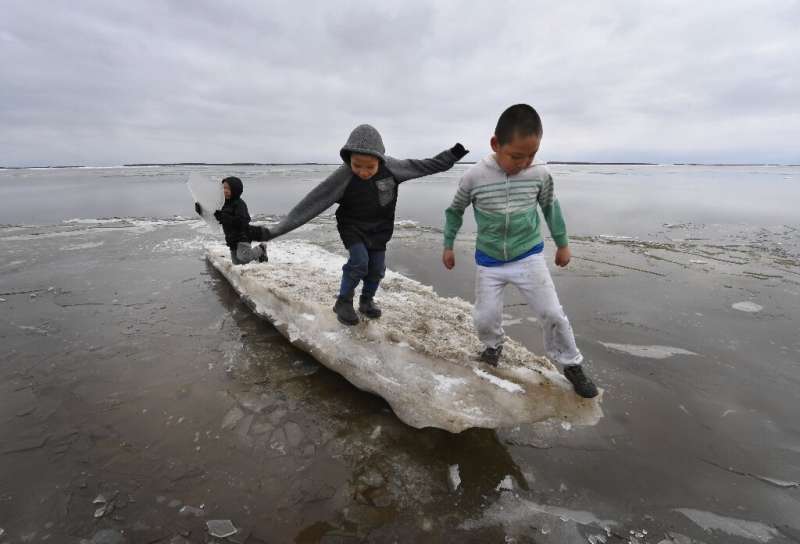 Schoolchildren play on melting ice at Yupik Eskimo village of Napakiak on the Yukon Delta in Alaska, where climate change threat