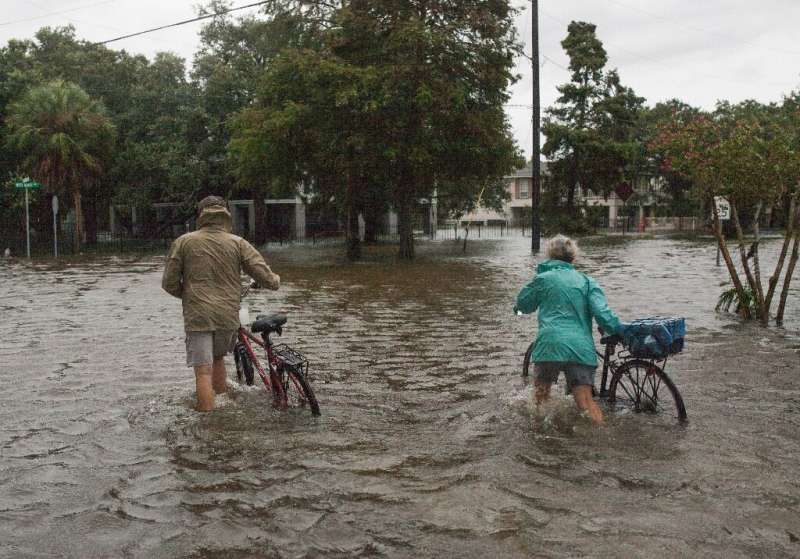 A couple walks their bikes through a flooded street after major storm Barry came ashore in Mandeville, Louisiana on July 14, 201