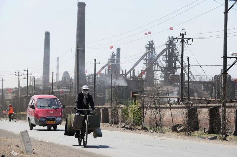 A cyclist is pictured in 2011 riding along a dusty road where dozens of factories process rare earths, iron and coal on the outs