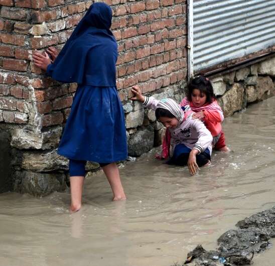 Afghan girls try to make their way home throught flooded streets in the Afghan capital, Kabul