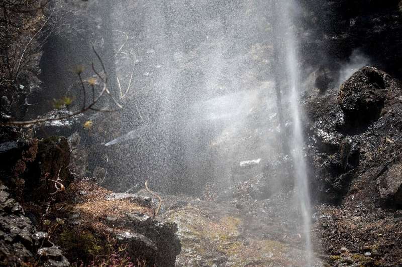 A firefighter douses a forest affected by wildfires in Gran Canaria on the Spanish Canary Islands on August 13, 2019