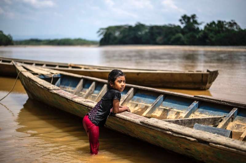 A girl of the Arazaire indigenous group—one of the 38 groups in Madre de Dios region—leans on a dugout canoe in the Inambari riv