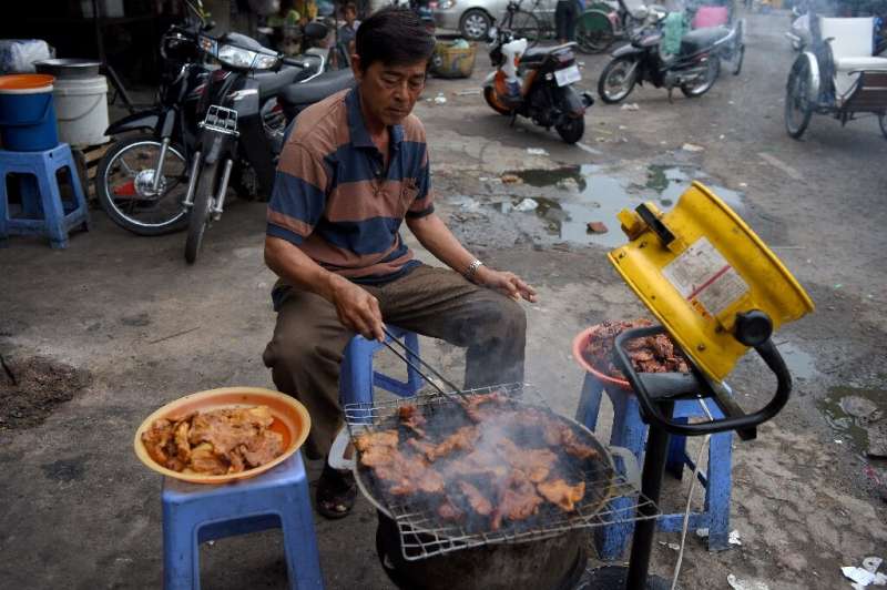 A man grills pork for sale at a market in Phnom Penh, Cambodia, which has banned the import of all pigs and pork products