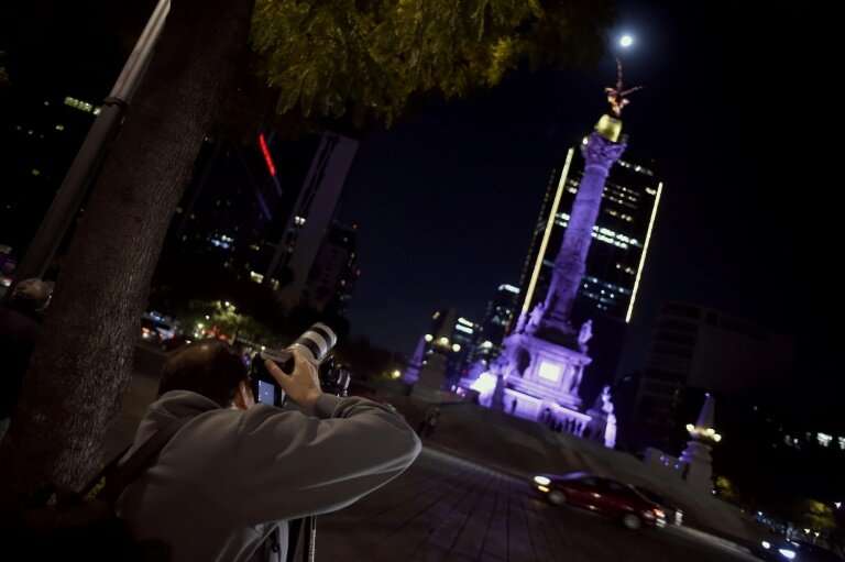 A man taking pictures of the Super Moon during the start of the total lunar eclipse, at the Angel de la Independencia in Mexico 