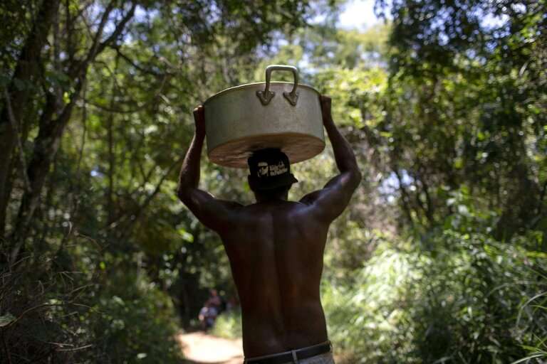 A member of the Pataxo Ha-ha-hae community carrying a cooking pan along a path through the forest