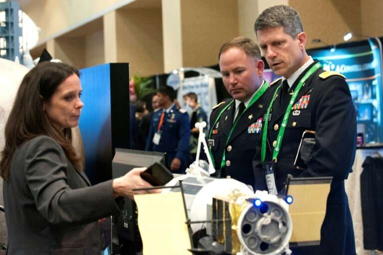A NASA exhibitor discusses the features of a rocket with members of the US military during the 35th Space Symposium in Colorado,