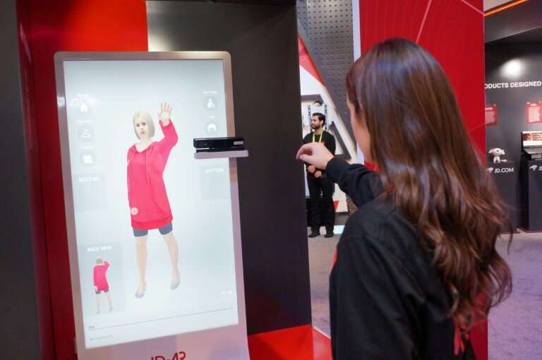 An employee of Chinese tech giant JD.com shows an augmented reality system that allows customers to virtually try on clothing at