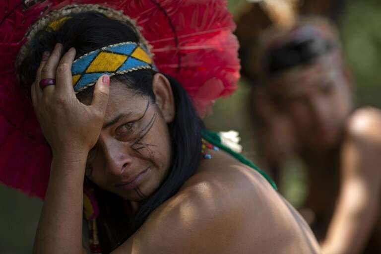 An indigenous woman of the Pataxo Ha-ha-hae community crying as she looks out over the Paraopeba river, filled with mud after a 