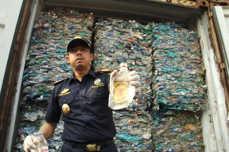 An Indonesian customs officer shows contaminated plastic waste from a container at Jakarta's international seaport