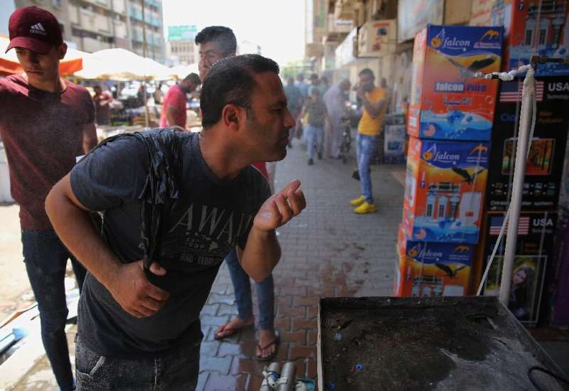 An Iraqi man uses a curbside shower to cool off