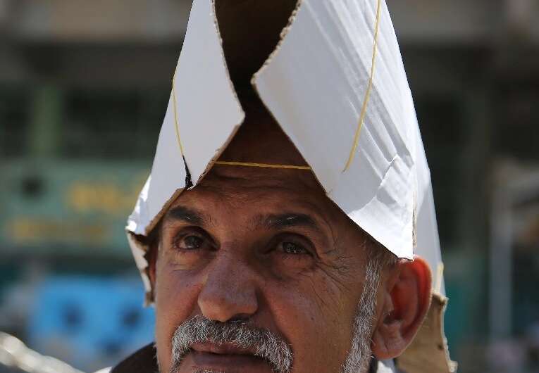 An Iraqi street vendor protects his head from the sun by using a piece of cardboard
