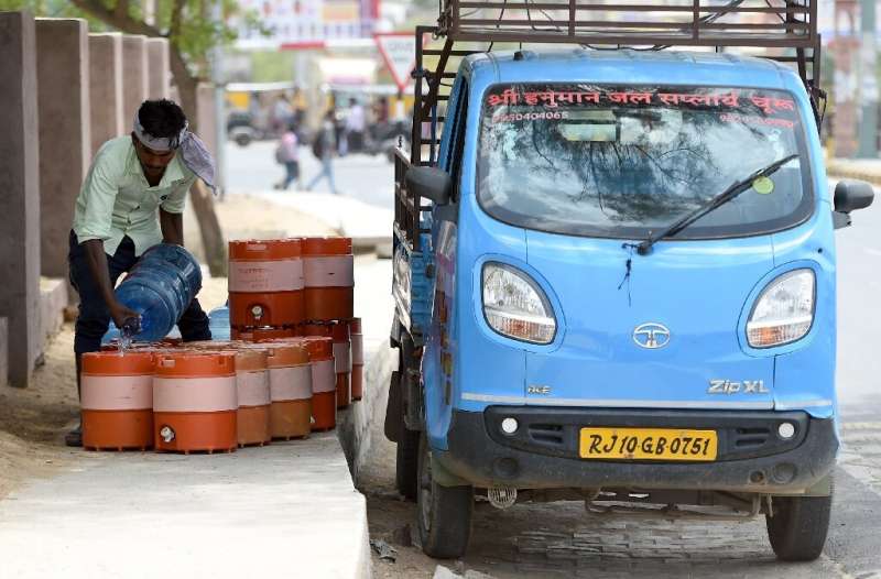 An man fills containers with water on a roadside in Churu, Rajasthan, which is sweltering under a heatwave