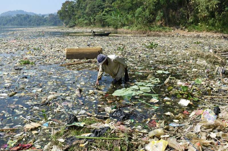 A scavenger collects plastic waste for recycling on the Citarum river, which is choked with garbage and industrial waste, in Ban