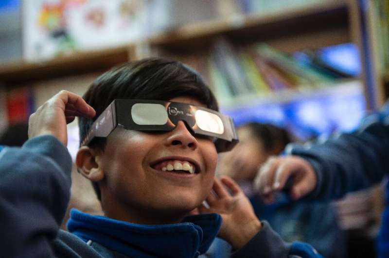 A schoolboy tries on special sunglasses at the Pedro Pablo Munoz school in La Higuera, Coquimbo Region, Chile, on the eve of a s