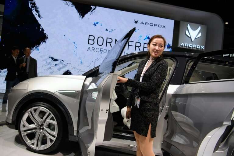 A visitor posing next to a car at the booth of Chinese carmaker Arcfox
