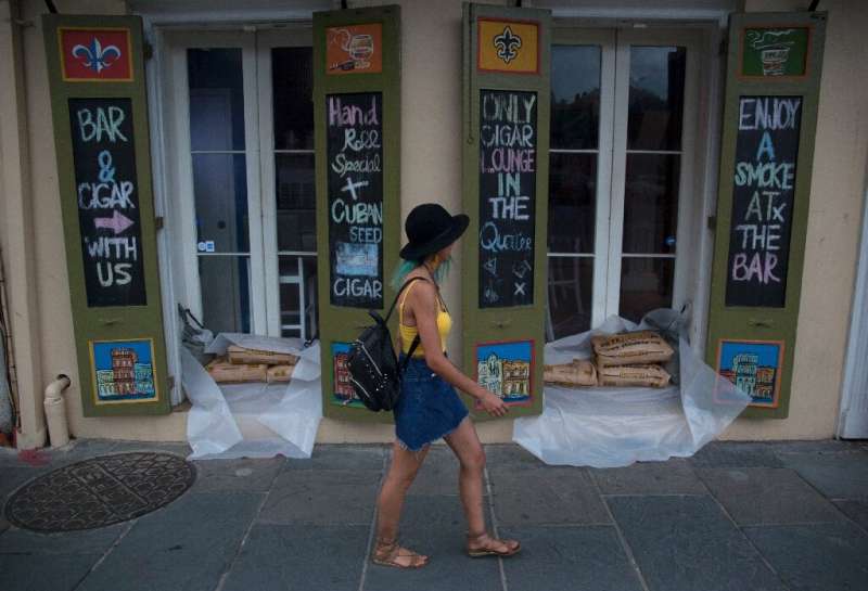 A woman walks past a cigar lounge and bar protected by sand bags in the French Quarter of New Orleans, in preparation for tropic