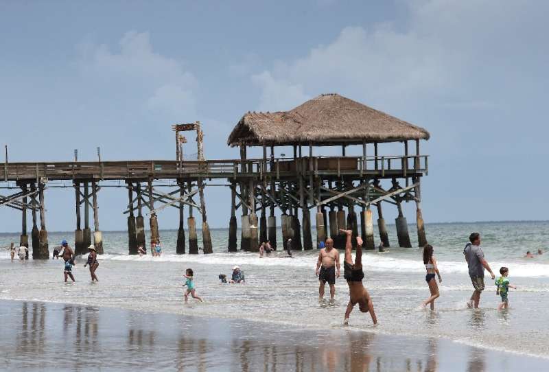 Beach-goers play in the surf near the Cocoa Beach Pier ahead of the arrival of Hurricane Dorian