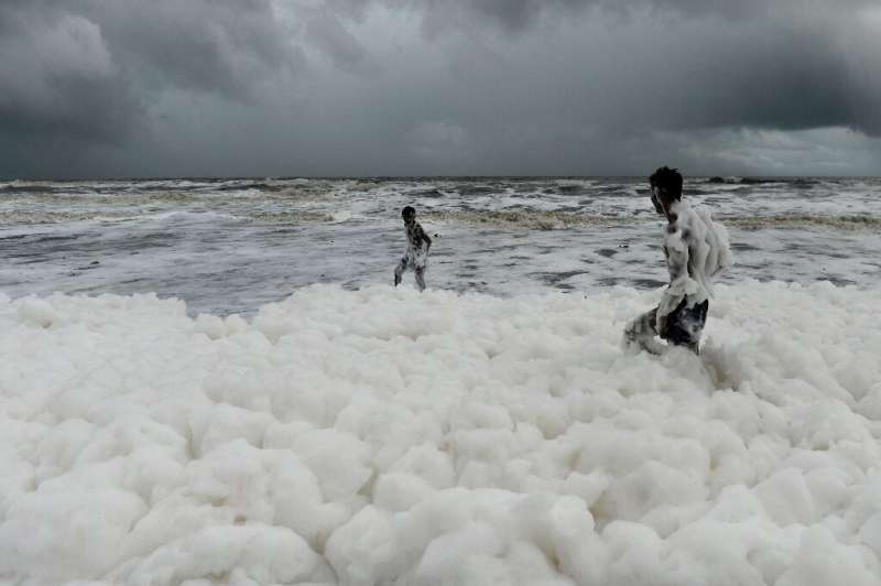 Children have been playing and taking selfies in the clouds of white suds on Marina Beach, even though they give off an acrid sm