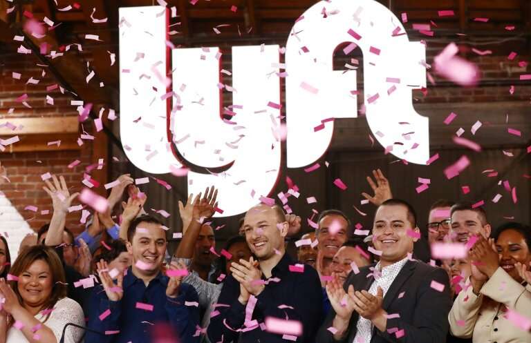 Confetti falls as Lyft CEO Logan Green (C) and President John Zimmer (LEFT C) ring the Nasdaq opening bell celebrating the compa