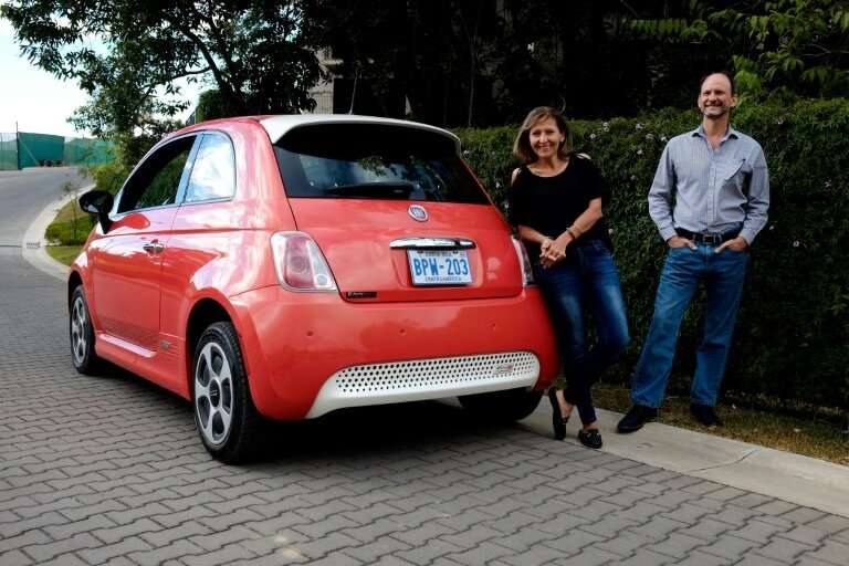 Costa Rican Erick Orlich (R) and his wife Gioconda Rojas (L) run two electric cars powered by solar panels installed on the roof