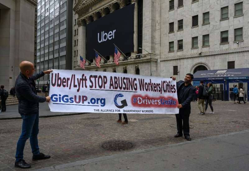 Drivers hold up a protest sign in front of the New York Stock Exchange to express displeasure over ride-hailing working conditio