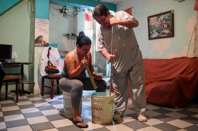 Francis Guillen and her father mix the chemicals to make the hairspray she will sell to supplement her meagre nurse's salary