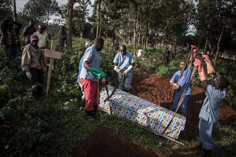 Gloved health workers conduct the burials and keep the loved ones at a safe distance