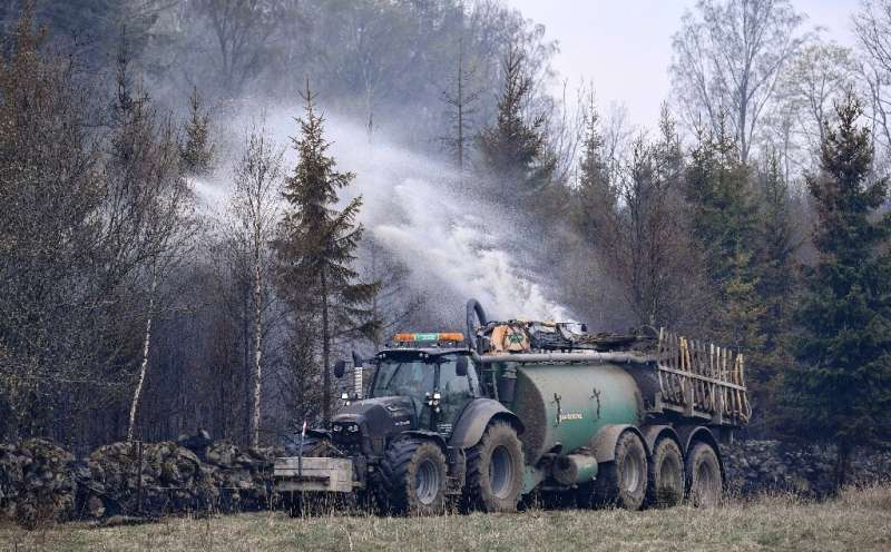 In Sweden, tractors hauling fertilizer tanks filled with water are used to put out a forest fire