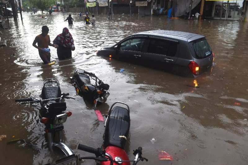 Lahore residents wade through a flooded street after heavy monsoon rains in the Pakistan city