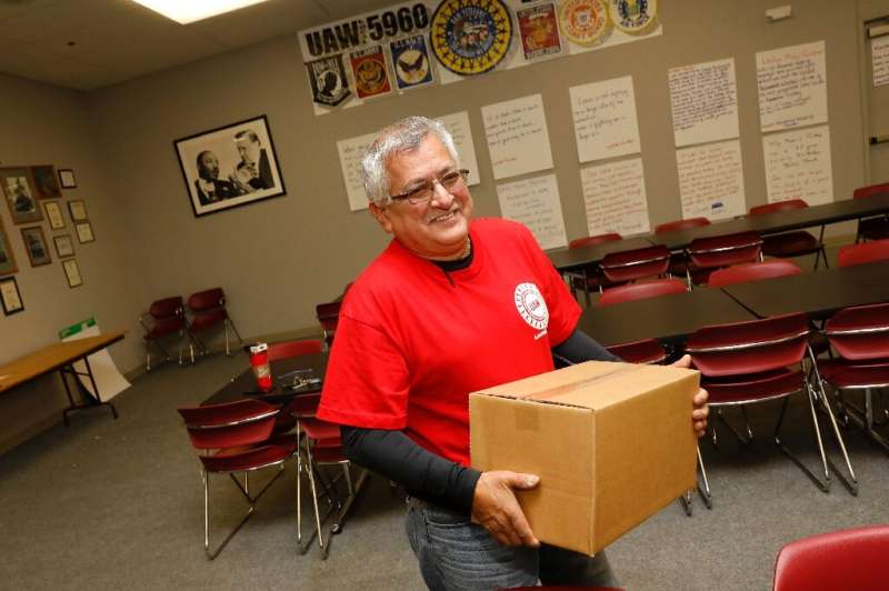 Louis Rocha, president of the UAW Local 5960, carries a box of food supplies for a striking worker on October 11 in Lake Orion, 