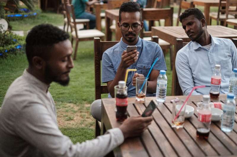Mohamed Omar (L) sits with his friends at a cafe in an upscale district of Sudan's capital on June 17, 2019