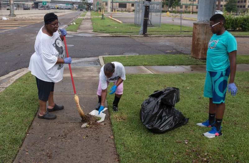 New Orleans residents clean up debris in their yard after flash floods struck the area early on July 10