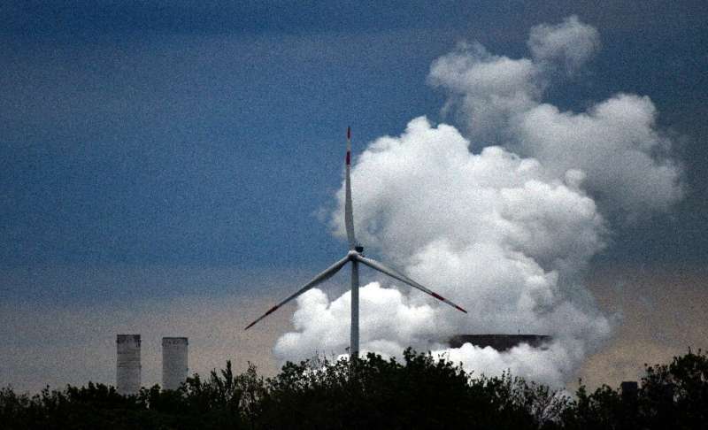 Old and new: a wind turbine and a coal-fired electricity plant in Germany
