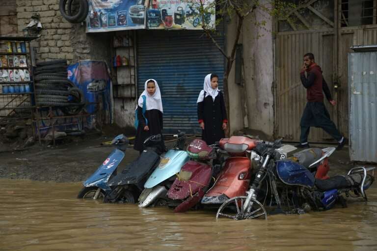 Pedestrians look for dry ground on a street after heavy rains in Kabul