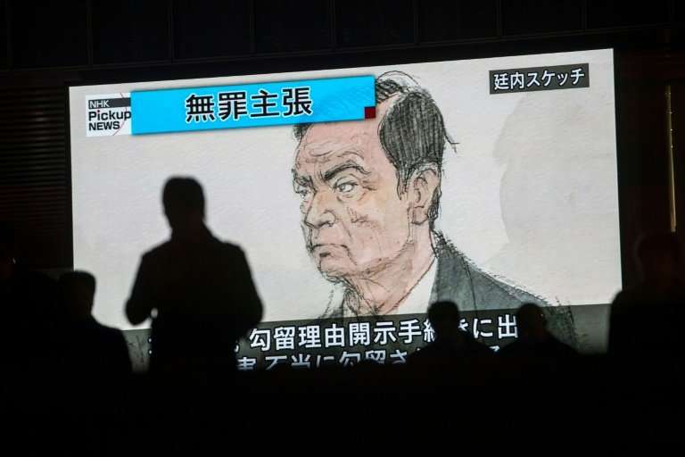Pedestrians pass a screen displaying a sketch of former Nissan chief Carlos Ghosn in the Tokyo courtroom on Tuesday
