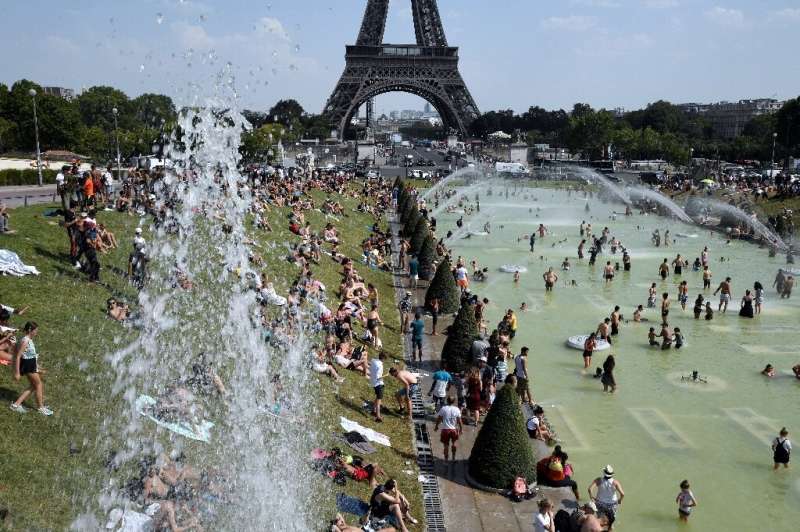 People cool off and sunbathe by the Trocadero Fountains next to the Eiffel Tower in Paris, on July 25 during a massive heat wave