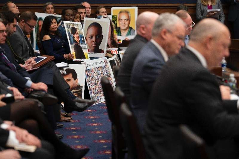 People hold up pictures of the victims of Boeing 737 MAX accidents as Federal Aviation Administration Administrator(FAA) Stephen