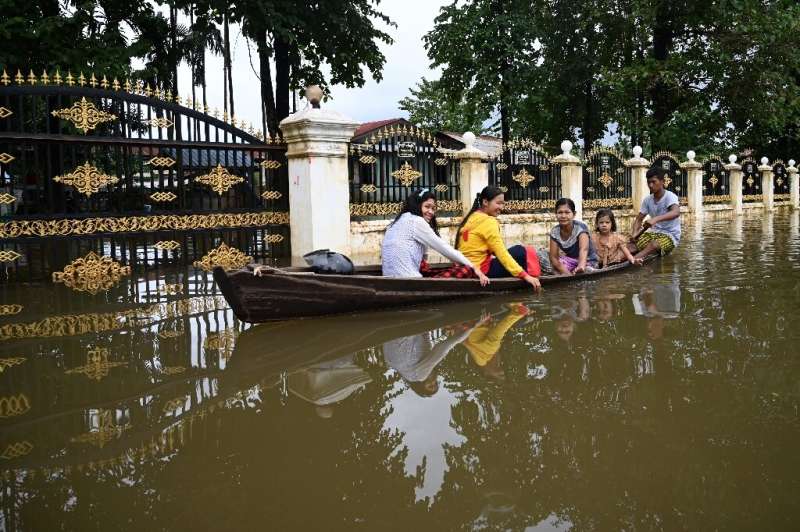 Residents ride in a boat through flooded streets in Shwegyin township in the Bago Region of Myanmar