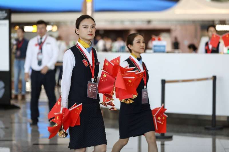 Staffers walk with national flags during the first day of operations at Beijing's new airport, which is seen as an embodiment of