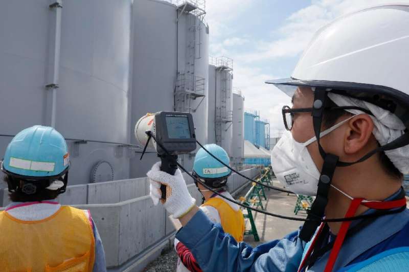 Staff measure radiation levels around the storage tanks of radiation-contaminated water at the tsunami-crippled Tokyo Electric P