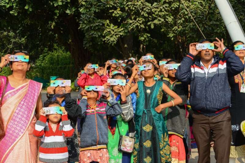 Students and teachers use solar filter glasses to look at the &quot;ring of fire&quot; solar eclipse at Gujarat Science City on 